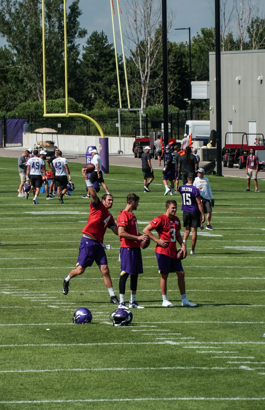 Football players perform training drills on an outdoor field.