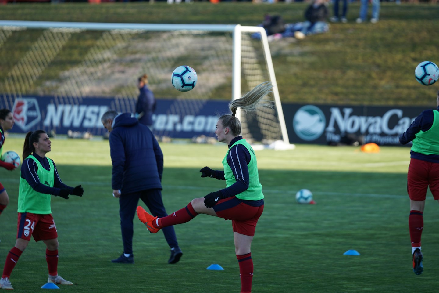 Soccer players practice drills on a grassy outdoor field.