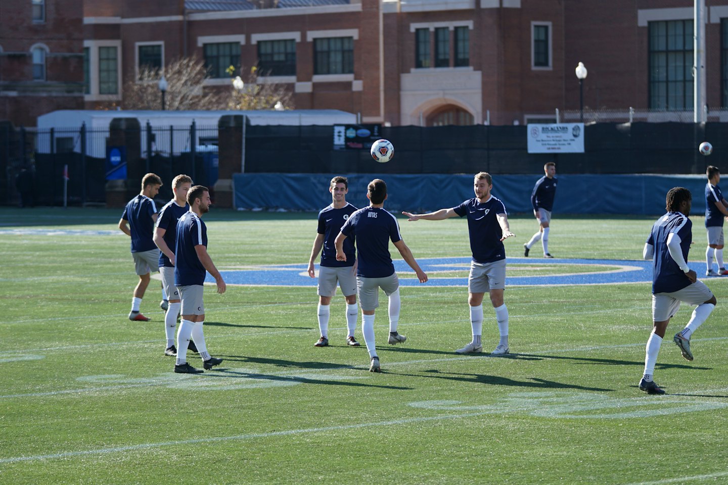 Soccer players practice headers on an artificial turf field.